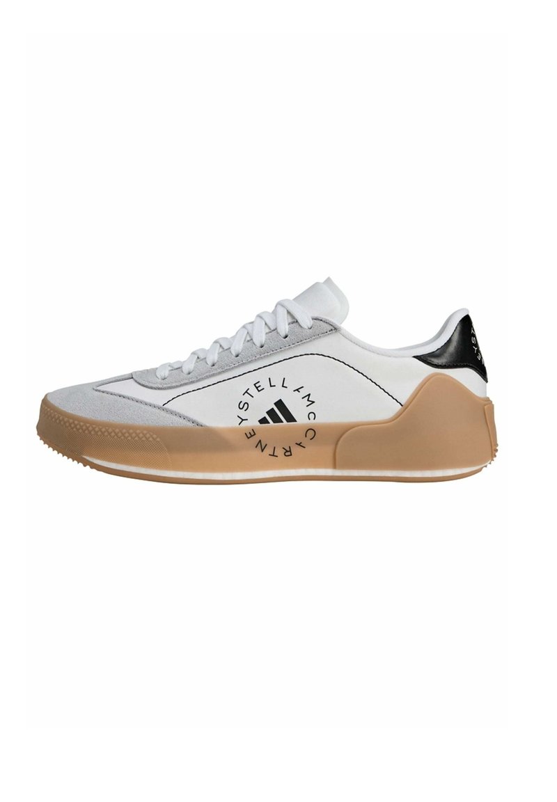 White sneaker with grey suede accents, black heel detail, and tan rubber sole. Features lace-up design and printed logo on the side.