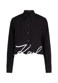 Zwart cropped shirt met lange mouwen, knoopsluiting aan de voorkant en een grote witte geborduurde "Karl" logo op de zoom. Zachte, gladde stof.