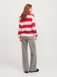Pull rayé rouge et blanc avec une coupe ample, associé à un jean taille haute gris à jambes larges. Texture douce et design décontracté.