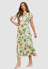 Vestido maxi floral con escote en V, mangas ligeras, detalle de cintura de crochet y dobladillo en capas. Predominantemente blanco con flores verdes y naranjas.