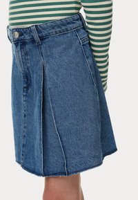 Gonna di jeans blu chiaro, con design plissettato, lunghezza media e orlo grezzo. Vita con dettaglio del bottone in metallo.