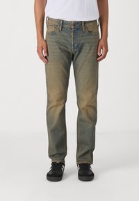 Blå denimbukser med en avslappet passform, falmet tekstur, standard fem lommer design og rette ben. Brukt med svarte joggesko.