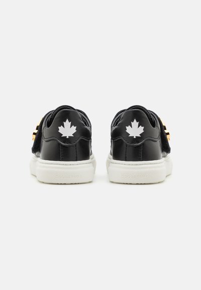 Schwarze Ledersneaker mit einer weißen Sohle, die ein schwarz-weißes Blattlogo auf der Rückseite und goldene Hardware-Akzente aufweisen.