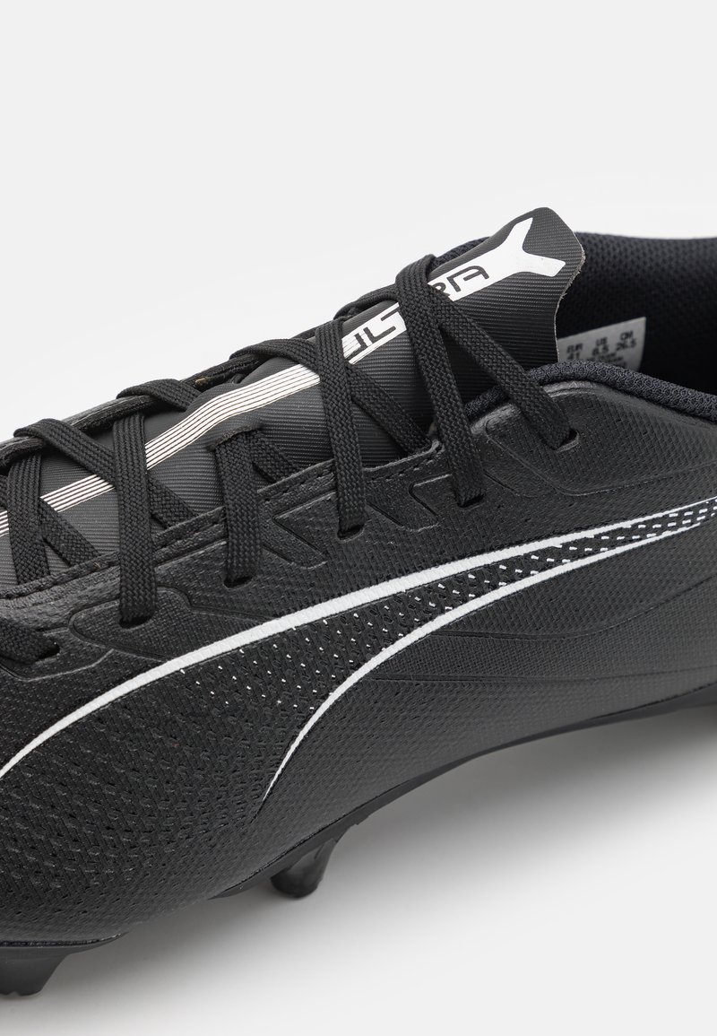 Crampons de football noirs avec une tige texturée, au design épuré, lignes d'accentuation blanches et lacets noirs. Présente une construction légère et des crampons moulés.