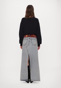 Denimová maxi sukně s vysokým rozparkem, má barevný vzorovaný pás a klasický design s pěti kapsami. Vyrobena ze světle modrého denimu.