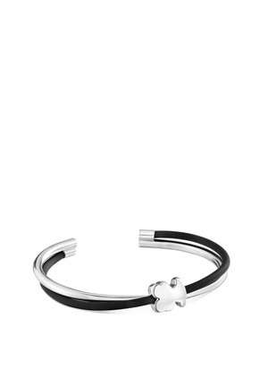 Bracelet manchette ouvert argent et noir avec une petite décoration en trèfle à quatre feuilles en argent sur fond blanc.