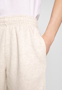 Lichtbeige sweatpants gemaakt van zachte stof, met een elastische tailleband en zijzakken, in een ontspannen pasvorm en met een subtiele textuur.