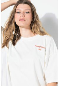 Camiseta blanca de gran tamaño hecha de algodón, con texto bordado en naranja "sunday picnic club" situado en el pecho. Textura suave.