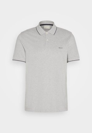 Szürke pólóing puha anyagból, két gombos gallérral, tengerészkék díszítéssel a galléron és az ujjakon, valamint diszkrét logóhímzéssel.