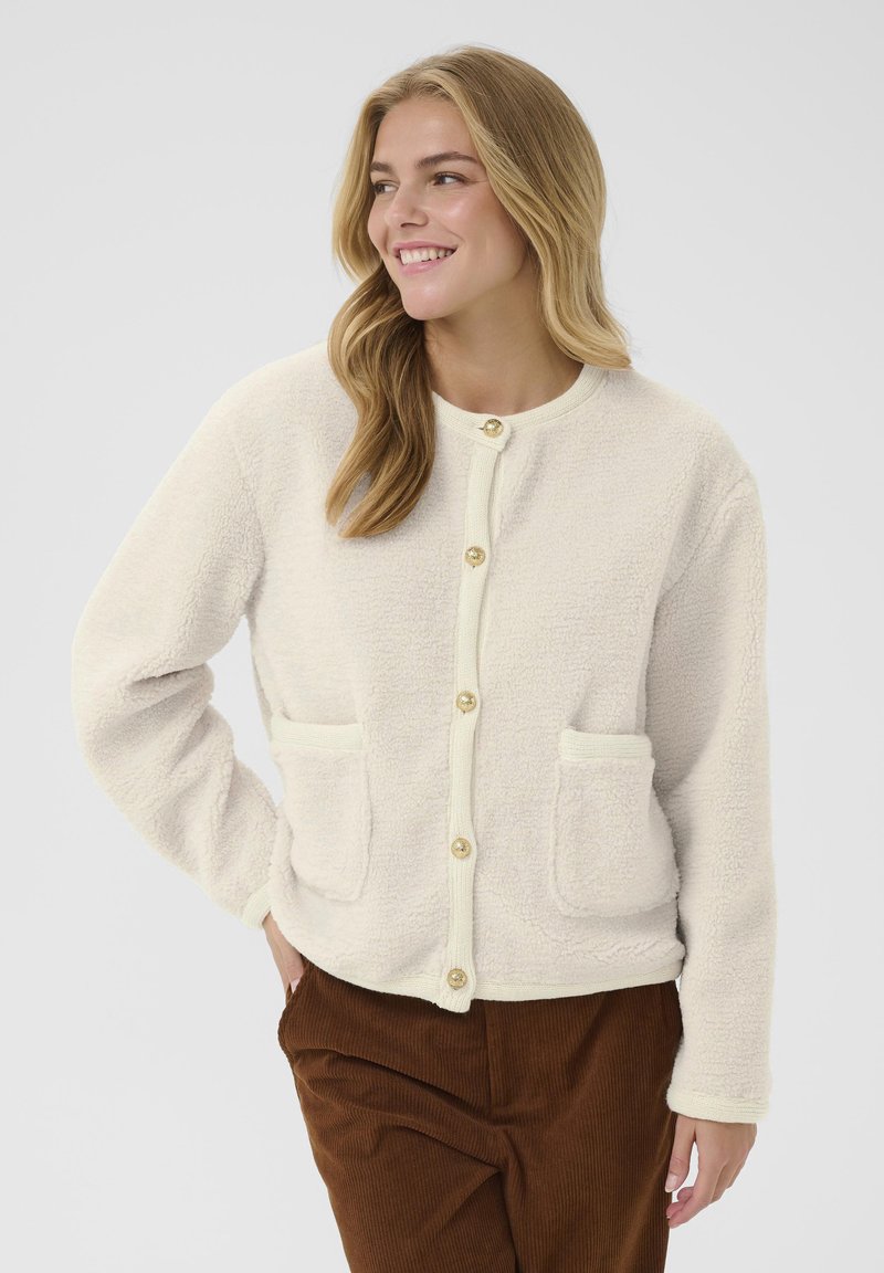 Cremefarbene Fleece-Jacke mit Rundhalsausschnitt, Knopfverschluss und zwei Fronttaschen. Strukturiertem Stoff mit gerippten Akzenten.