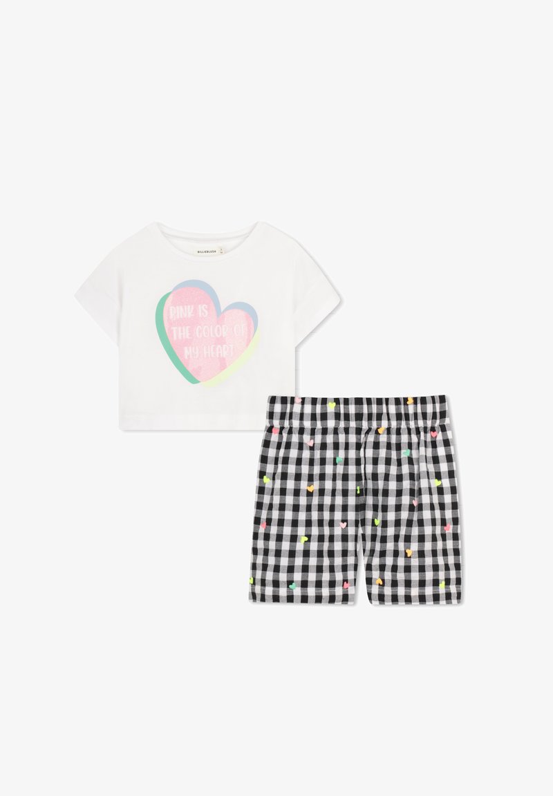 Λευκό κοντό μπλουζάκι με επικαλυπτόμενες καρδιές και κείμενο, σε συνδυασμό με ασπρόμαυρα καρό σορτς με μικρές πολύχρωμες καρδιές.