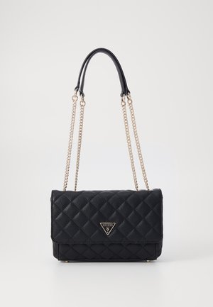 Sac d'épaule noir matelassé avec bandoulières en chaîne dorée et logo Guess sur le rabat avant sur fond blanc.