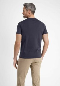 Navy short-sleeve T-shirt made from cotton blend, featuring a round neckline and a fitted shape, paired with beige trousers.