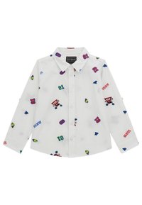 Witte overhemd met knopen, voorzien van kleurrijke geborduurde patches, waaronder cijfers, iconen en de merknaam "GUESS" in het rood, met lange mouwen.