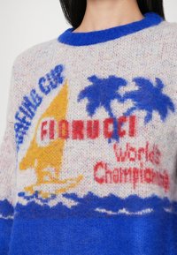 Puloveris su geltonu jachtu, mėlynomis palmėmis, mėlynomis bangomis ir raudonais užrašais "FLORIDA! Pasaulio čempionas" pilkai mėlyname fone.