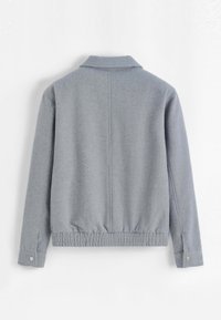 Veste en maille grise avec col, taille élastiquée et poignets à boutons. Design simple avec une texture lisse et un style minimaliste.