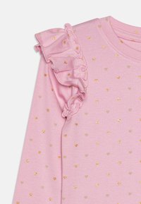 Roze langarmtop met ruches op de schouders, voorzien van gouden en beige hartvormige patronen. Zachte katoenmix textuur.