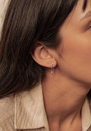 Rosenvergoldete Ohrringe mit floralem Design, drei kleinen klaren Steinen, hängenden Ketten mit zusätzlichen Steinen und einer filigranen Textur.