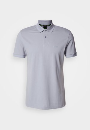 Gaišpelēka polo kreklā no kokvilnas ar klasisku apkakli un divu pogu aizdari. Mazs tonāls logotips uz krūtīm. Īsas piedurknes.