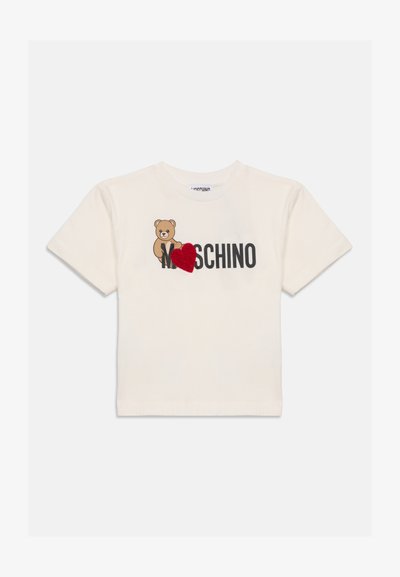 Кремаво късо с ръкав тениска с изображение на меченце и черен "Moschino" текст, с червено текстурирано сърце, покриващо част от текста.
