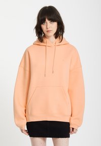 Pomarańczowa, overize'owa bluza z kapturem, z przednią kieszenią, regulowanym kapturem i ribbowymi mankietami. Gładka faktura, minimalistyczny design i dyskretne logo.