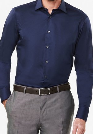 Marineblauwe langwerpige overhemd met een strak ontwerp, een button-down kraag en een subtiele glans, gecombineerd met grijze broek en een bruine riem.