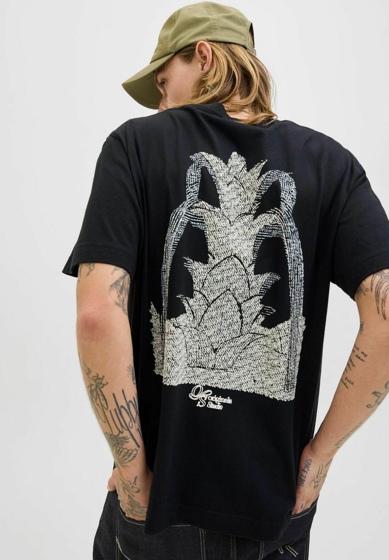 Camiseta de algodón negra con un diseño gráfico blanco de una planta en la parte posterior, mangas cortas y un ajuste relajado.