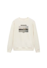 Kremna pulover s dolgimi rokavi, ki ima osrednji grafični napis "VELIKA JABOLKO" nad fotografijo obzorja mesta New York.