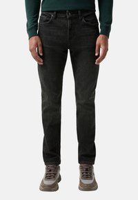 Černé džíny z denimu s přímým střihem, pěti kapsami, zapínáním na knoflík a jemným světlejším vyblednutím. Kombinované s šedými a hnědými teniskami.