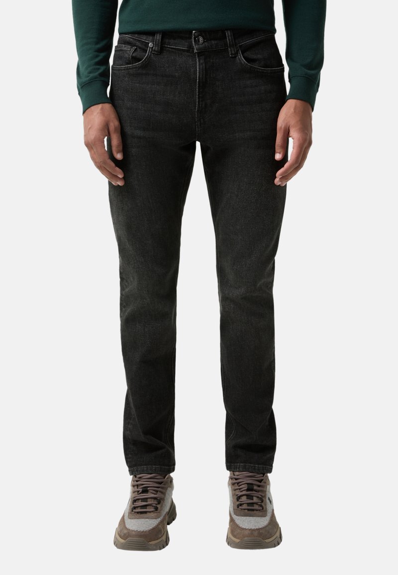 Černé džíny z denimu s přímým střihem, pěti kapsami, zapínáním na knoflík a jemným světlejším vyblednutím. Kombinované s šedými a hnědými teniskami.