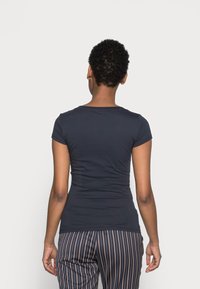 T-shirt ajustada de meia-sleeve em azul-marinho, feita de tecido suave, com decote redondo e costuras mínimas, combinada com calças listradas.