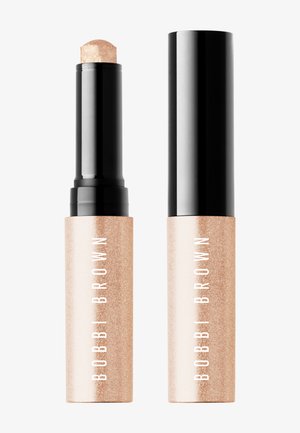 Enlumineur stick effet scintillant doré Bobbi Brown avec bouchon noir à vis, présenté ouvert et fermé sur fond blanc.