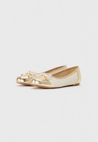 Sapatilhas de balé em material sintético creme com uma superfície texturizada e bico metálico dourado. Apresenta um laço com acabamentos dourados.