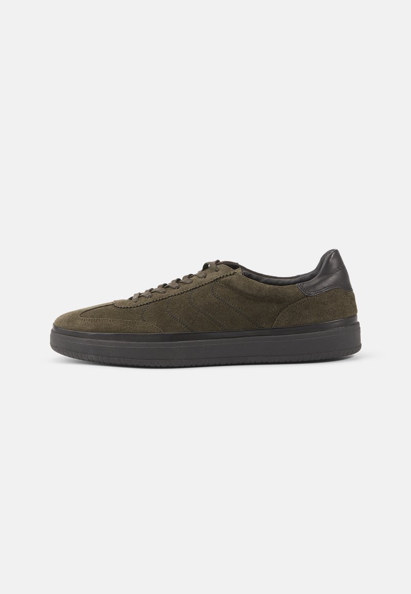 Olive green suede sneakers with black leather accents and laces, featuring a textured surface and a thick black rubber sole.