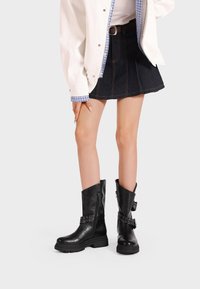 Stivali ankle in pelle nera con finitura leggermente lucida, dotati di borchie decorative in metallo e chiusura con zip su un lato. Design con suola spessa.