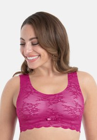 Fuksjowy koronkowy biustonosz typu bralette z falowanym obszyciem, szerokimi ramiączkami i małą satynową kokardką na środku przodu. Lekki, z kwiatowym wzorem.