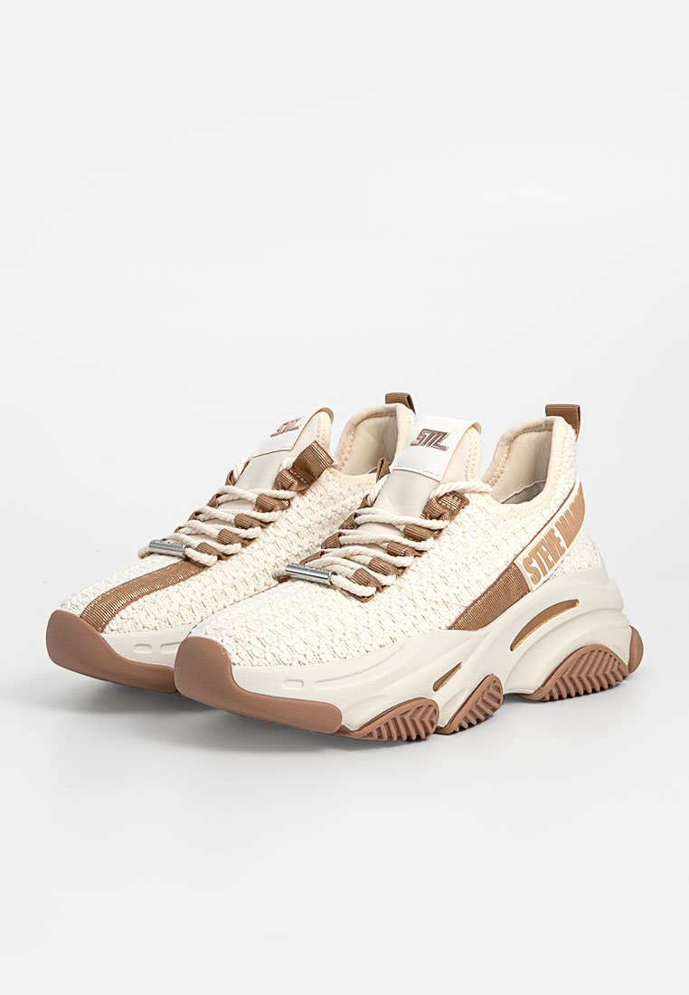 Szydełkowane sneakersy w kolorze kremowym z brązowymi akcentami. Cechują się teksturowaną cholewką, elastycznymi sznurówkami oraz grubą gumową podeszwą z falistym wzorem.