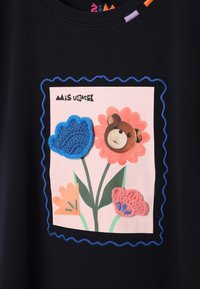 Tumesinine T-särk, millel on värvikas lilleline graafika ja heegeldatud detailid. Disainis on karu portree ja sakilised äärised.