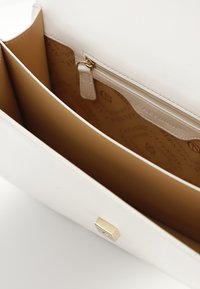 Hvid læder håndtaske med en glat overflade, der har en tanfarvet inderside, to rum og en lynlåslomme. Gyldne hardware-detaljer.