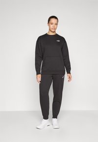 Svart sweatshirt och sweatpants i mjukt tyg. Har en känguruficka, ribbade mudd och en liten logotyp på bröstet och benet.