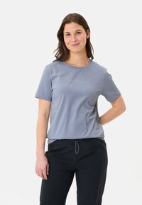 Light blue short-sleeve t-shirt with a round neck and subtle logo on the chest, paired with black pants featuring a drawstring waist.