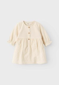 Krämfärgad babydress med långa ärmar, tre träknappar framtill och veckad midjedetalj.