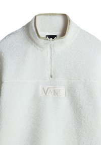 Polaire sherpa blanche à col montant avec zip quart et bordure beige sur le col, avec logo Vans embossé sur la poitrine.