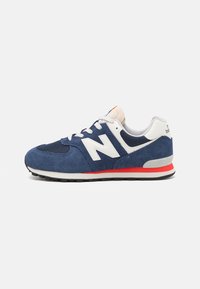 Baskets en daim et mesh bleu marine avec des accents blancs, arborant un logo "N" proéminent, une bande rouge sur la semelle intermédiaire, un design à lacets et une semelle en caoutchouc texturée.