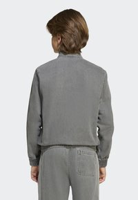 Veste en denim gris avec col montant, poignets côtelés et taille élastique. Fabriquée en tissu doux, elle présente un design simple et épuré.