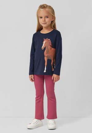 Langarmige marineblauwe shirt met een paardenprint, gecombineerd met roze ribgebreide broek en witte sneakers met opvallende veters.