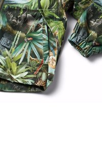 Jakke med et levende junglemønster med grønne bladværk, dyr og krybdyr. Lavet af et glat materiale med elastiske manchetter.