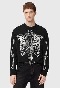 Zwarte trui met een witte skeletprint aan de voorkant, lange mouwen en een ronde hals. Soepele textuur, casual pasvorm.