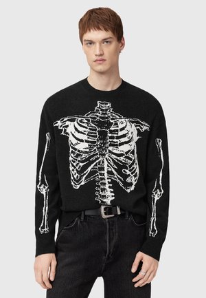 Pull noir avec un imprimé squelette blanc sur le devant, manches longues et design col rond. Texture lisse, coupe décontractée.