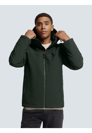 Dark green padded jacket with a high collar, front zipper, and side pockets. Worn over a light-colored sweater. Smooth, matte texture.